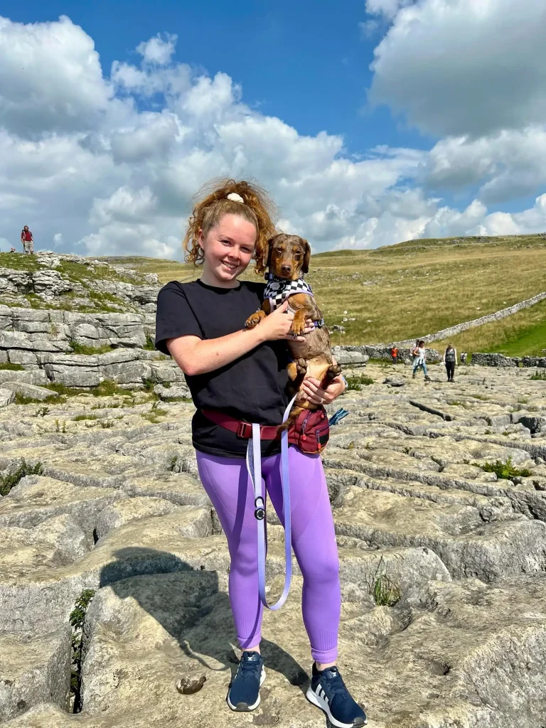 Photo of Emily, a behaviourist, with her brown Dachshund enjoying the outdoors